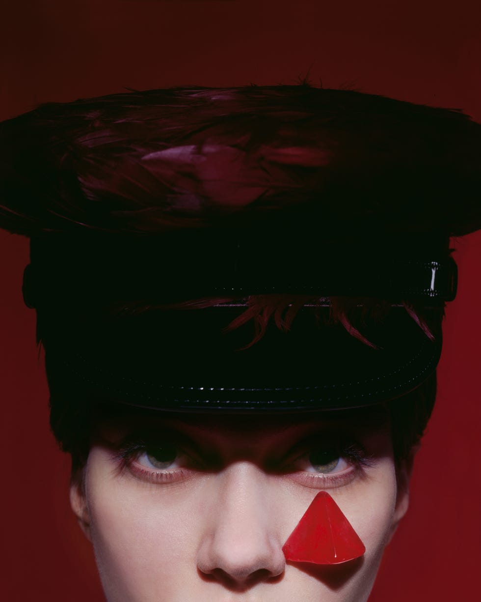 a close up of a woman in a hat with a triangular red shape below her eye