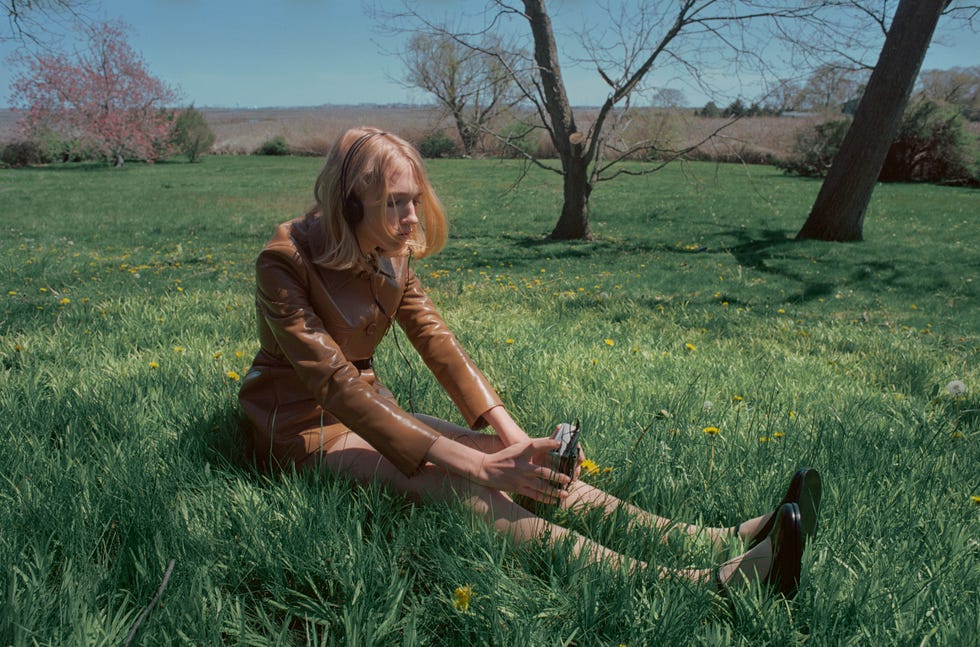 a woman sitting in the grass listening to music