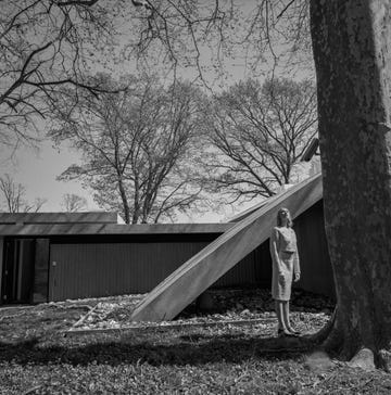 a black and white image of a woman standing in front of a modern building