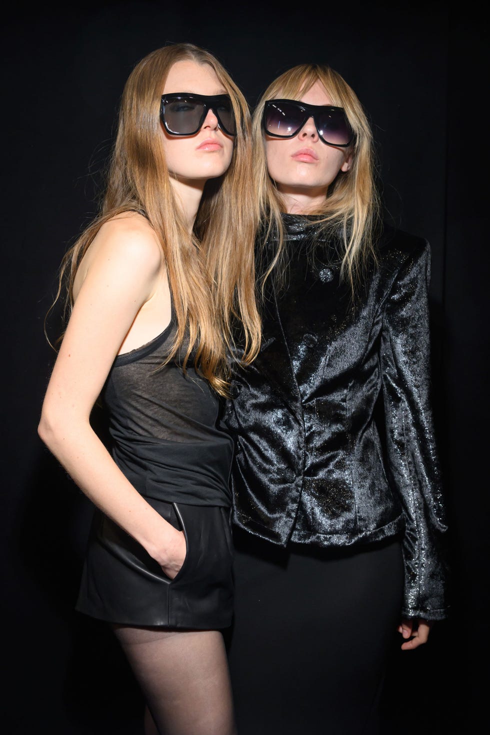 two individuals posing together in stylish outfits