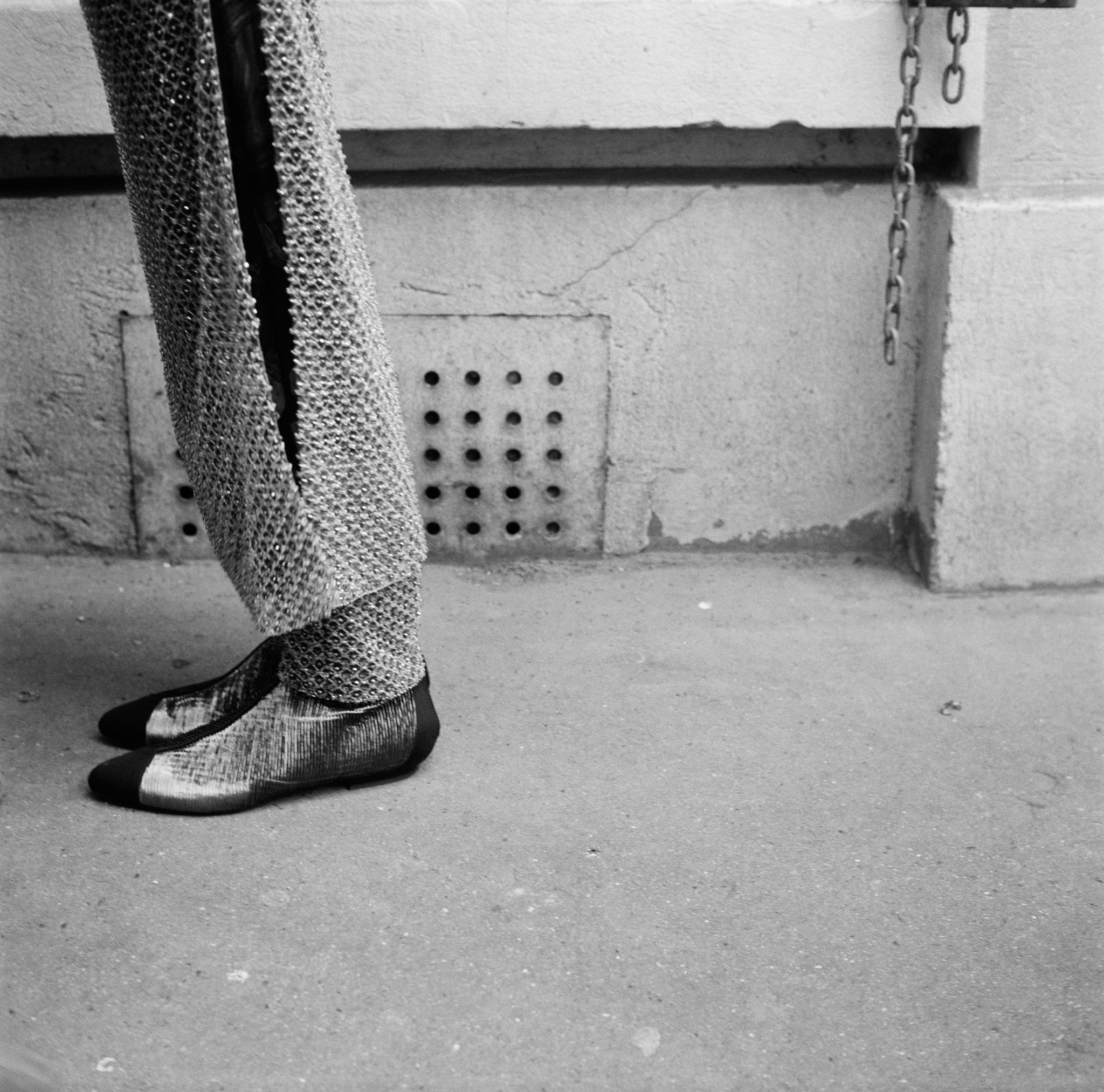 ein Schwarzweißbild der Hosenbeine und Schuhe einer Person
