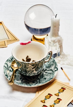 tea cup with a crystal ball candle and tarot cards on a table