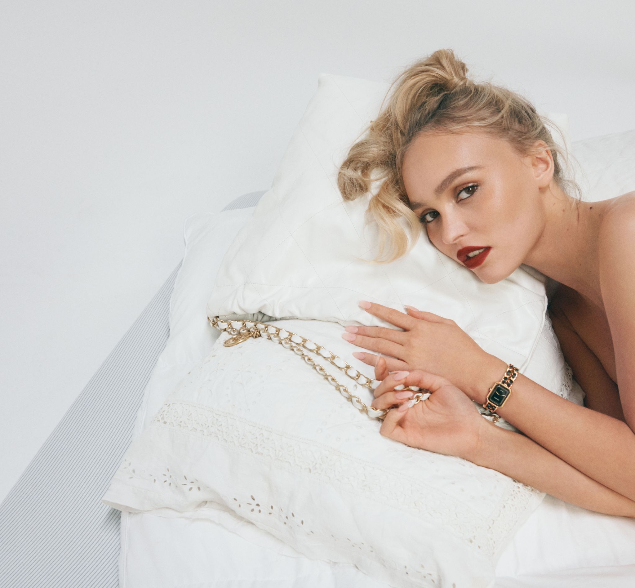 lily rose depp lies on a white pillow