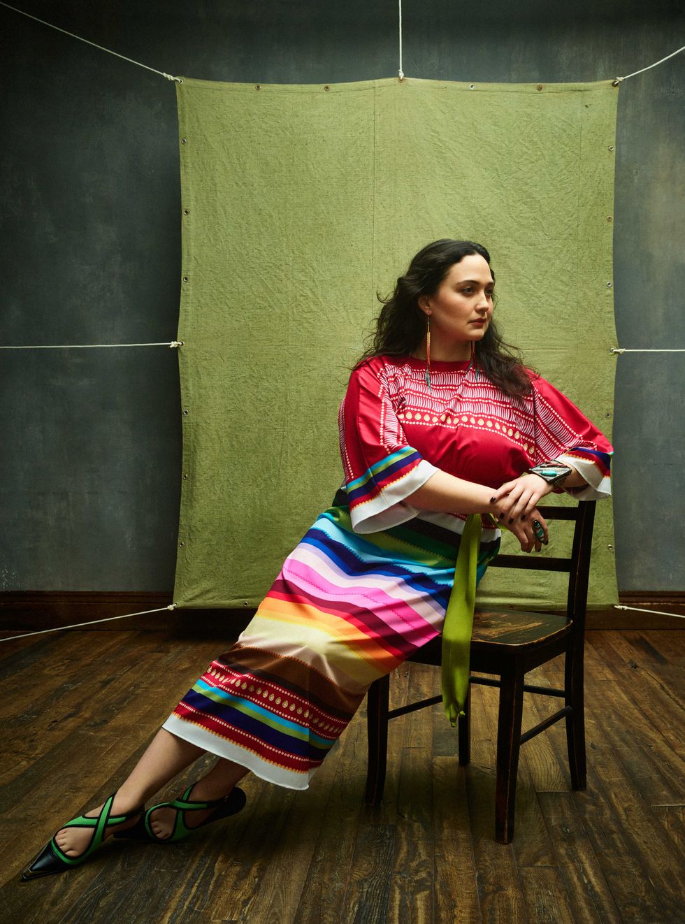 a woman sitting in a chair wearing a multicolored dress with stripes