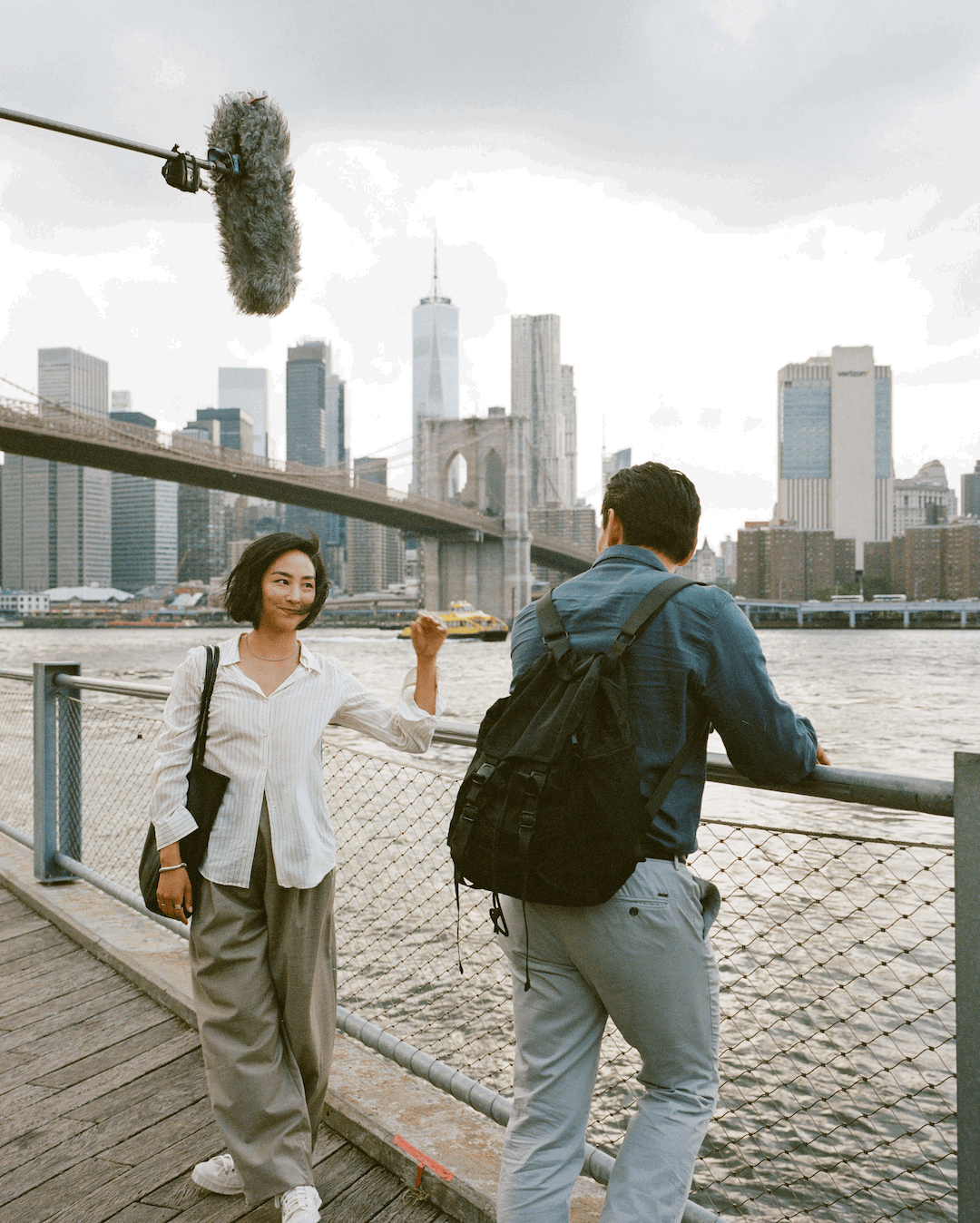 a woman in a white shirt and gray pants standing in front of a river