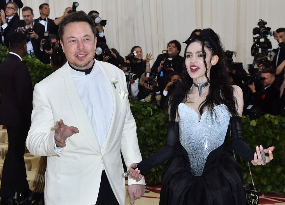 elon musk and grimes standing next to each other and smiling with a crowd of people around