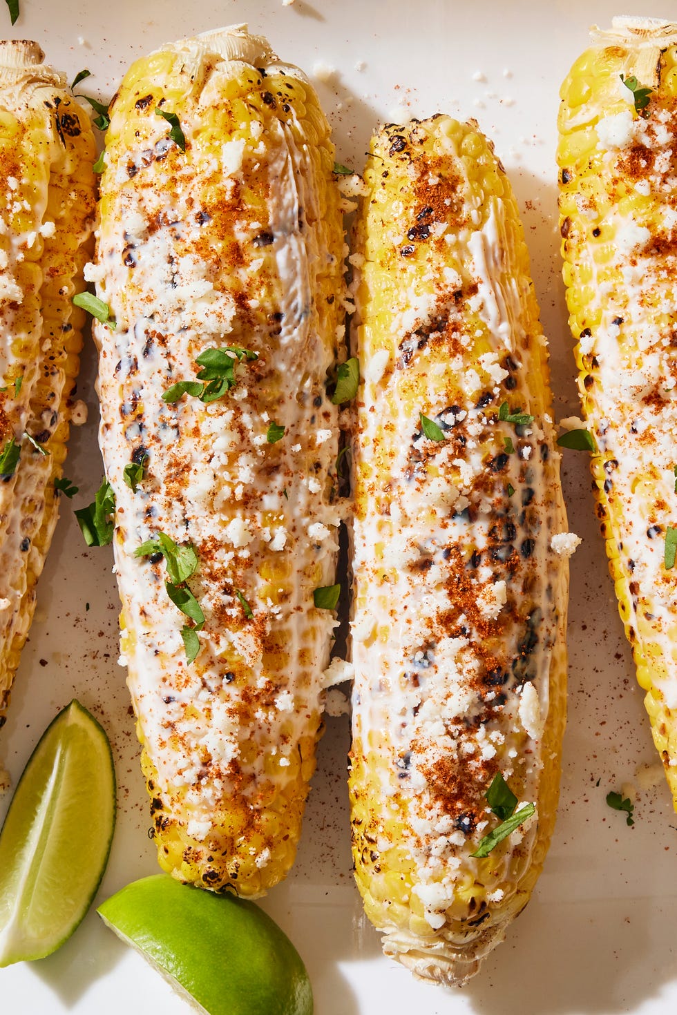 grilled corn topped with a creamy mixture, cotija cheese, chili powder, cilantro and lime