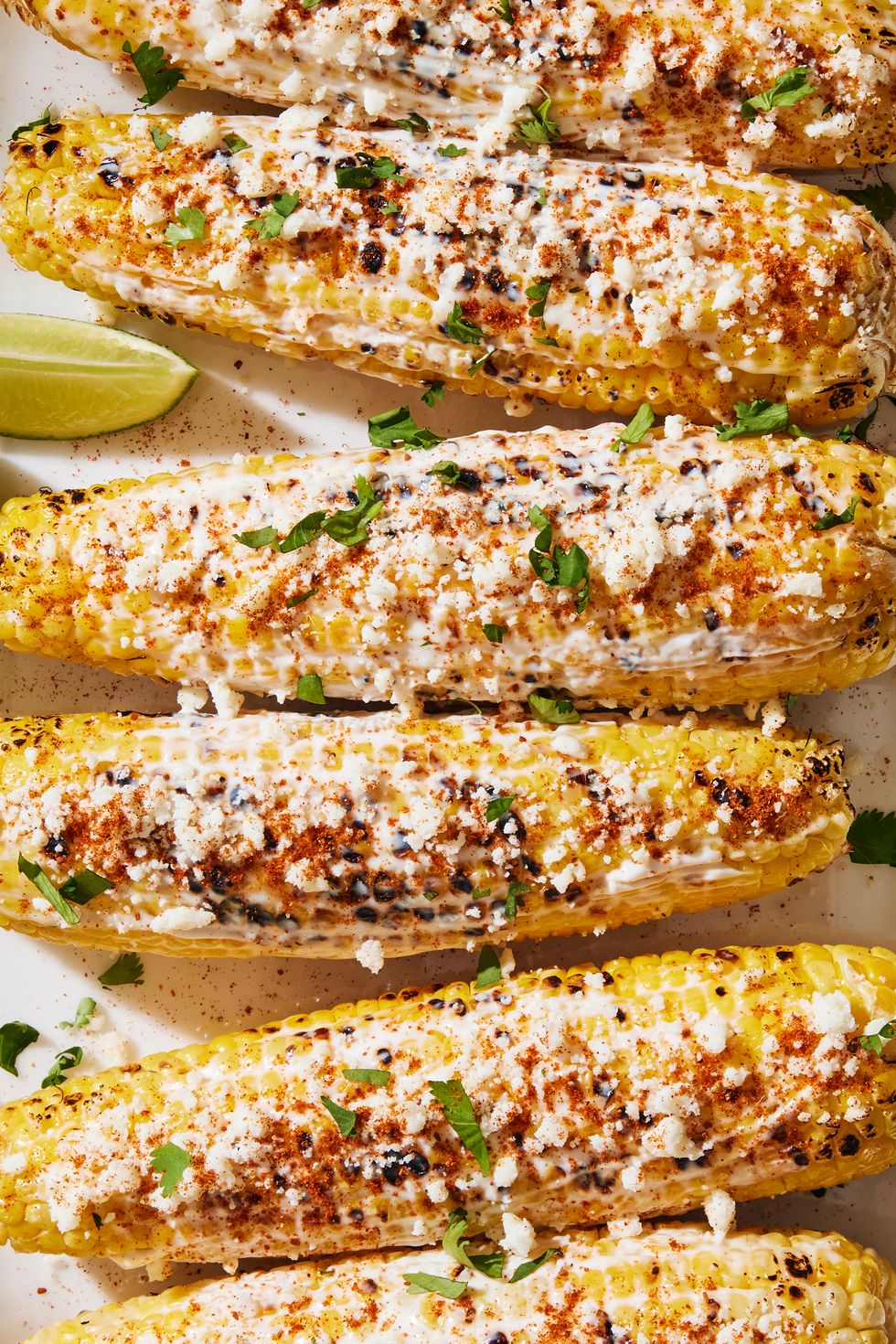 grilled corn topped with a creamy mixture, cotija cheese, chili powder, cilantro and lime