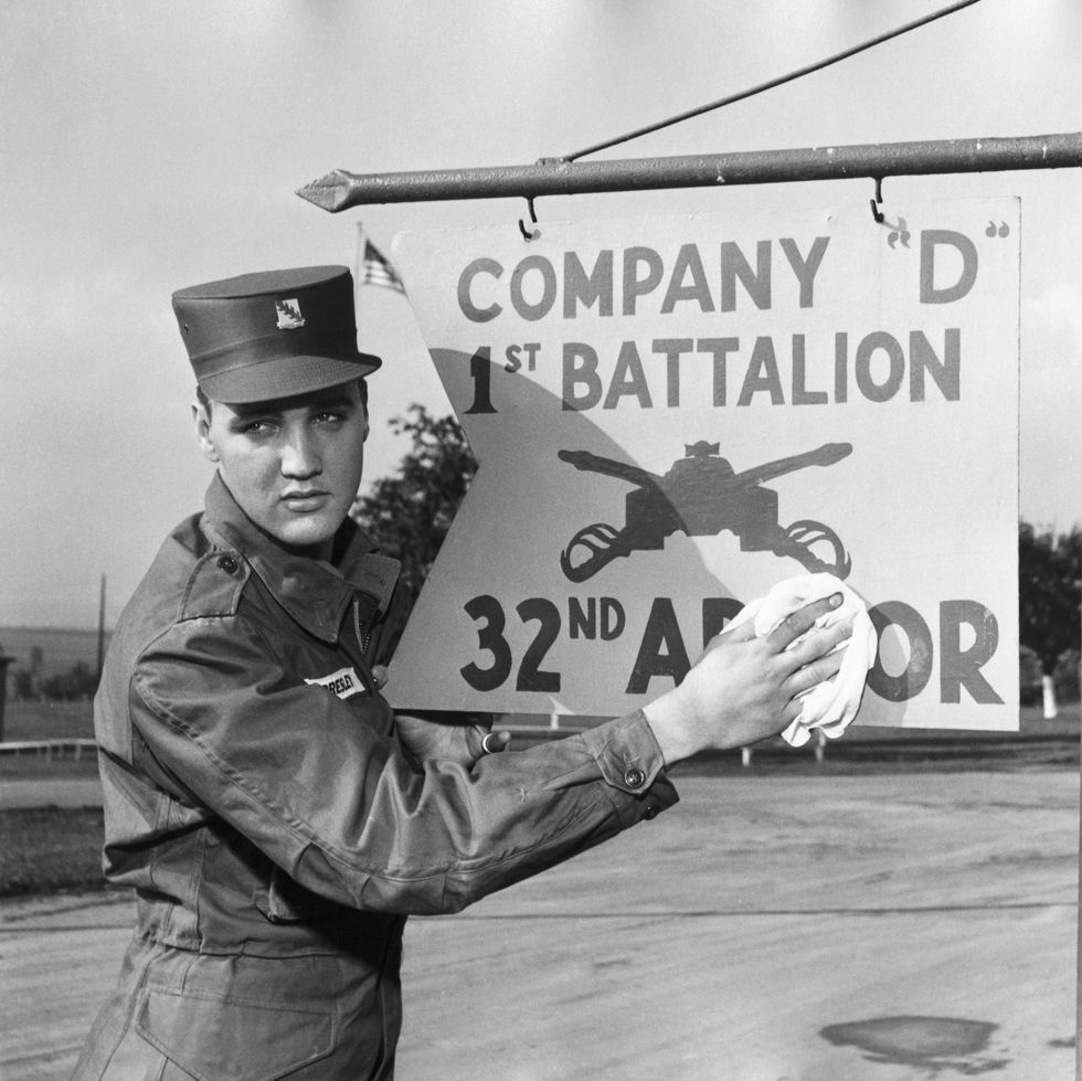 elvis presley in uniform wipes a sign that reads company 1st battalion 32rd