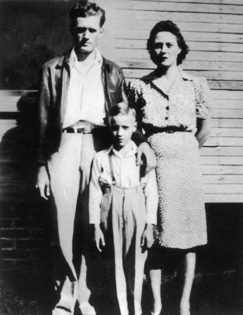 a man, a boy, and a woman stand together for a photo outside the side of a building