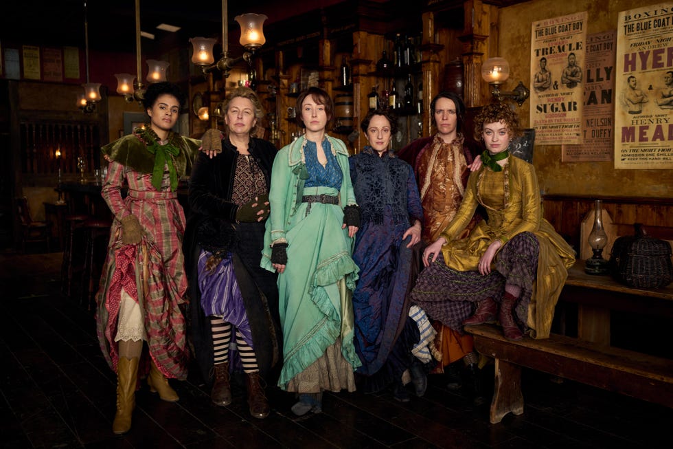 Group of individuals in vintage clothing posing in a rustic setting