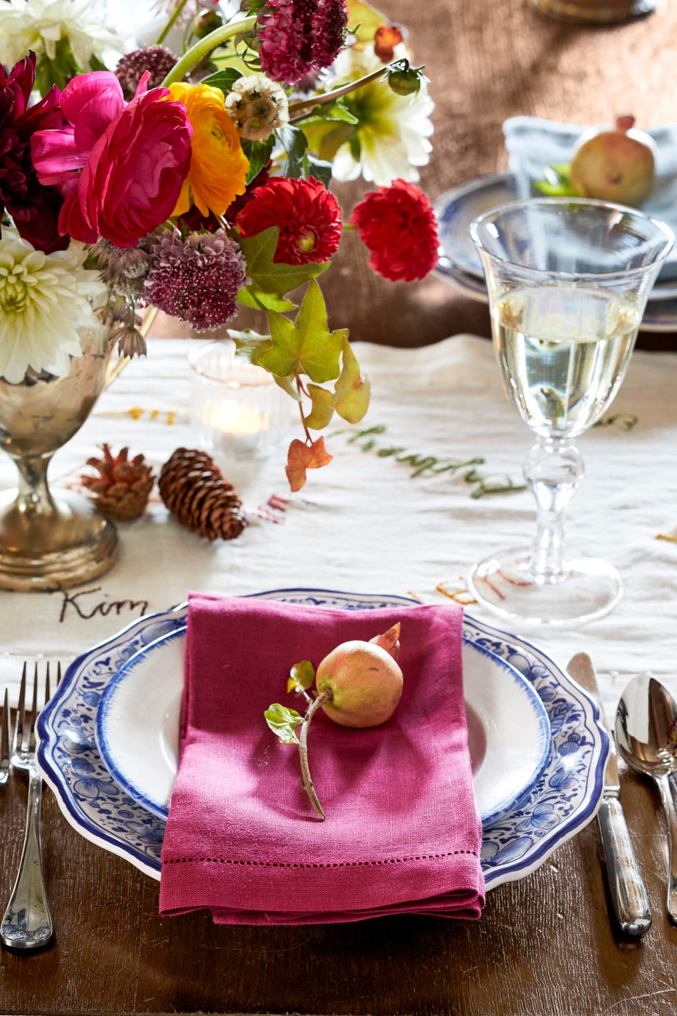 thanksgiving table with a floral centerpiece in a vintage trophy and a table runner with embroidered family names