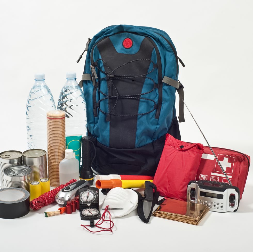 backpack with bottled water, cans of food, knife and more in front of it