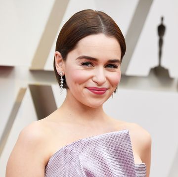 emilia clarke with short brown bobbed hair, dangly silver earings and sequined pink dress