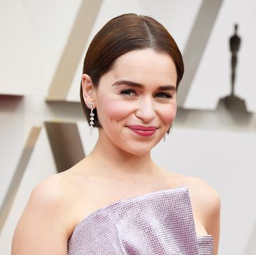 emilia clarke with short brown bobbed hair, dangly silver earings and sequined pink dress