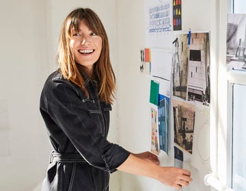 a person is standing beside a wall covered with a variety of pinned images