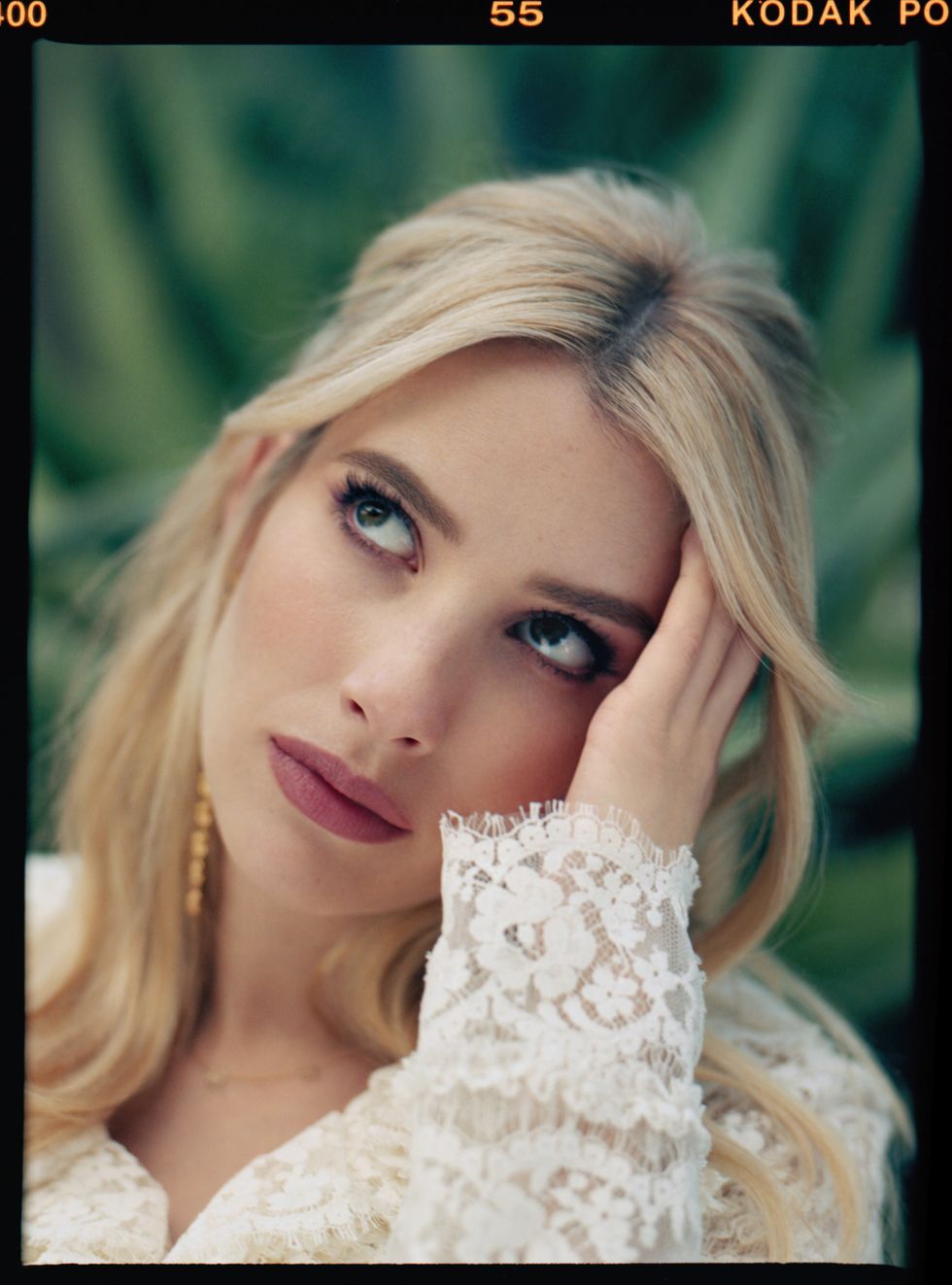close up portrait shot of emma roberts in white lace dress, with her hand on the side of her head