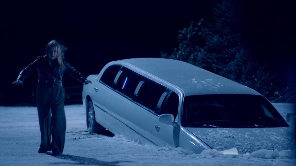 woman approaching a partially buried limousine in the snow