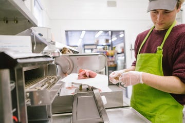 employee in general store weighing sliced meat in kitchen