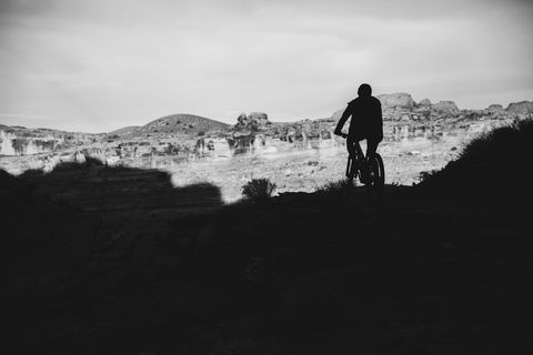 silhouette of biker on the whole enchilada trail in moab, utah