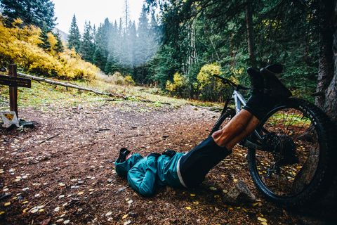 man lying on ground with legs propped against bike