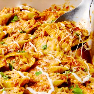 stuffed pasta shells with chicken, cheese, enchilada sauce, and a drizzle of sour cream