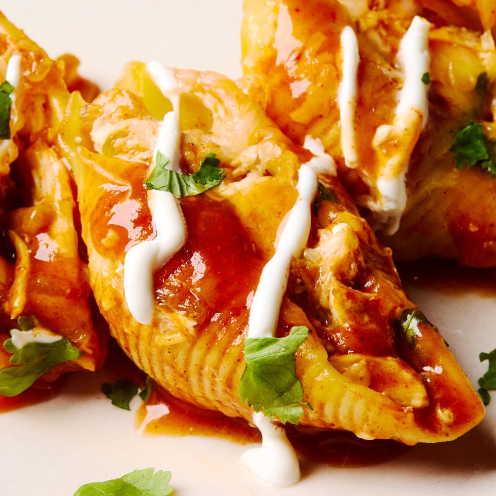 stuffed pasta shells with chicken, cheese, enchilada sauce, and a drizzle of sour cream
