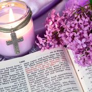 encouraging bible verses  bible open on a table with a candle, cross, purple flowers, and a purple tablecloth