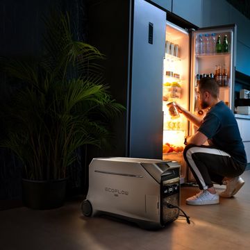 a person sitting on a stool next to a refrigerator