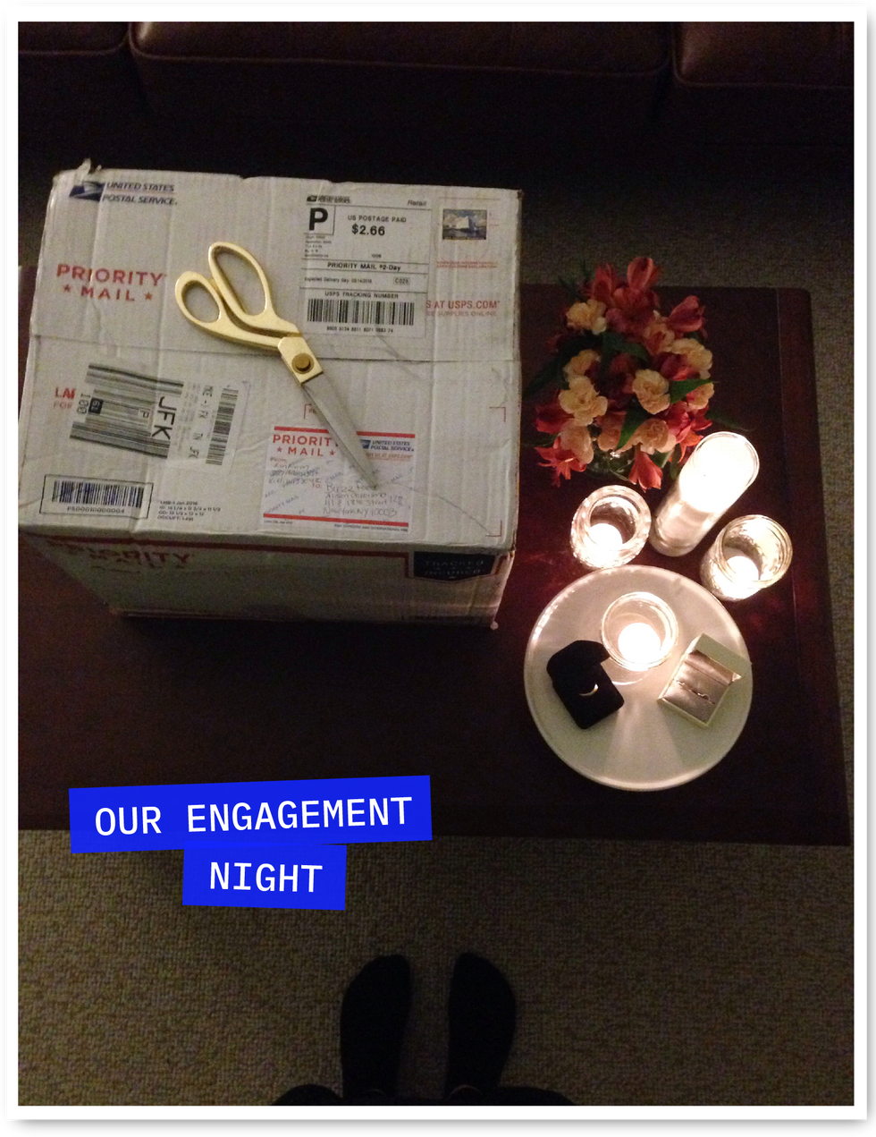 the engagement night. usps box with gold scissors on top and two rings placed on top of a candle lit table