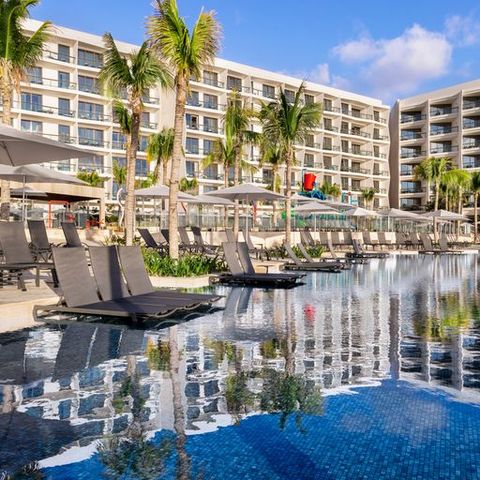 the hotel is reflected into the waters of the pool at the hilton cancun, a good housekeeping pick for best all inclusive family resorts