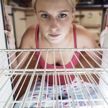 england, cornwall, young woman looking into empty fridge
