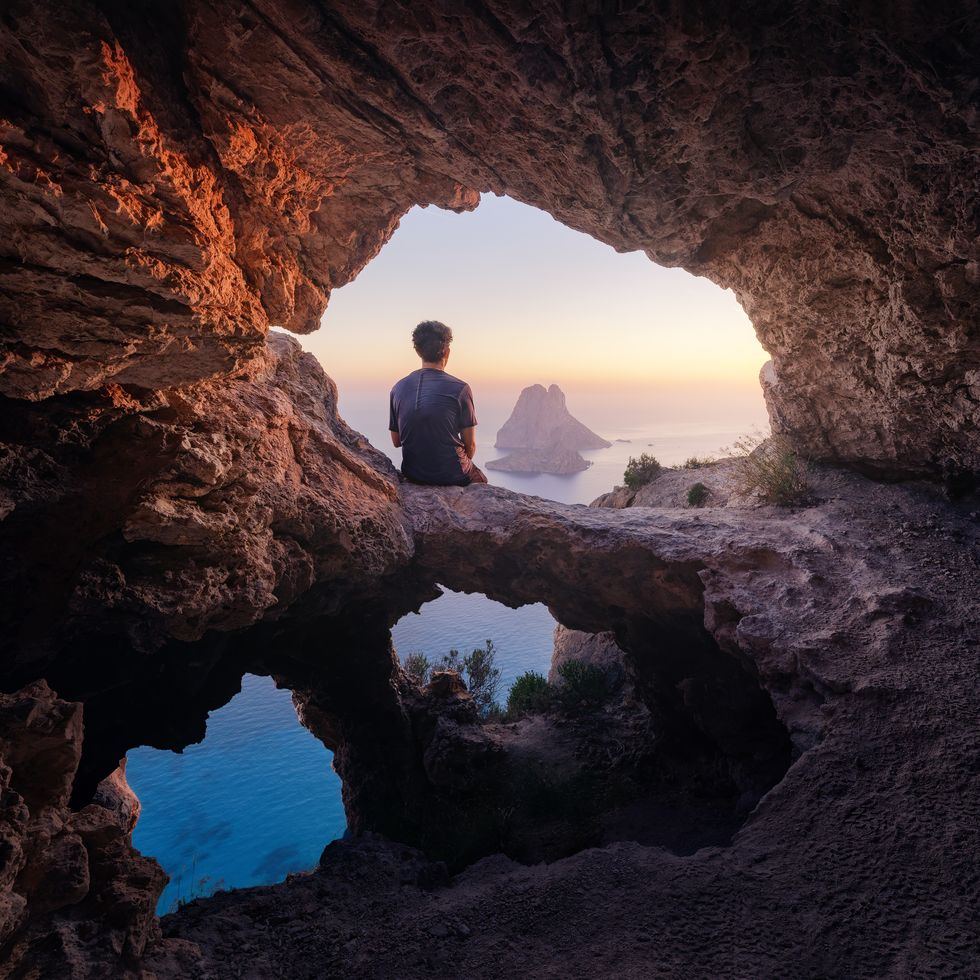 enjoying the sunset of es vedra inside a cave with 3 windows, ibiza, landscape photography