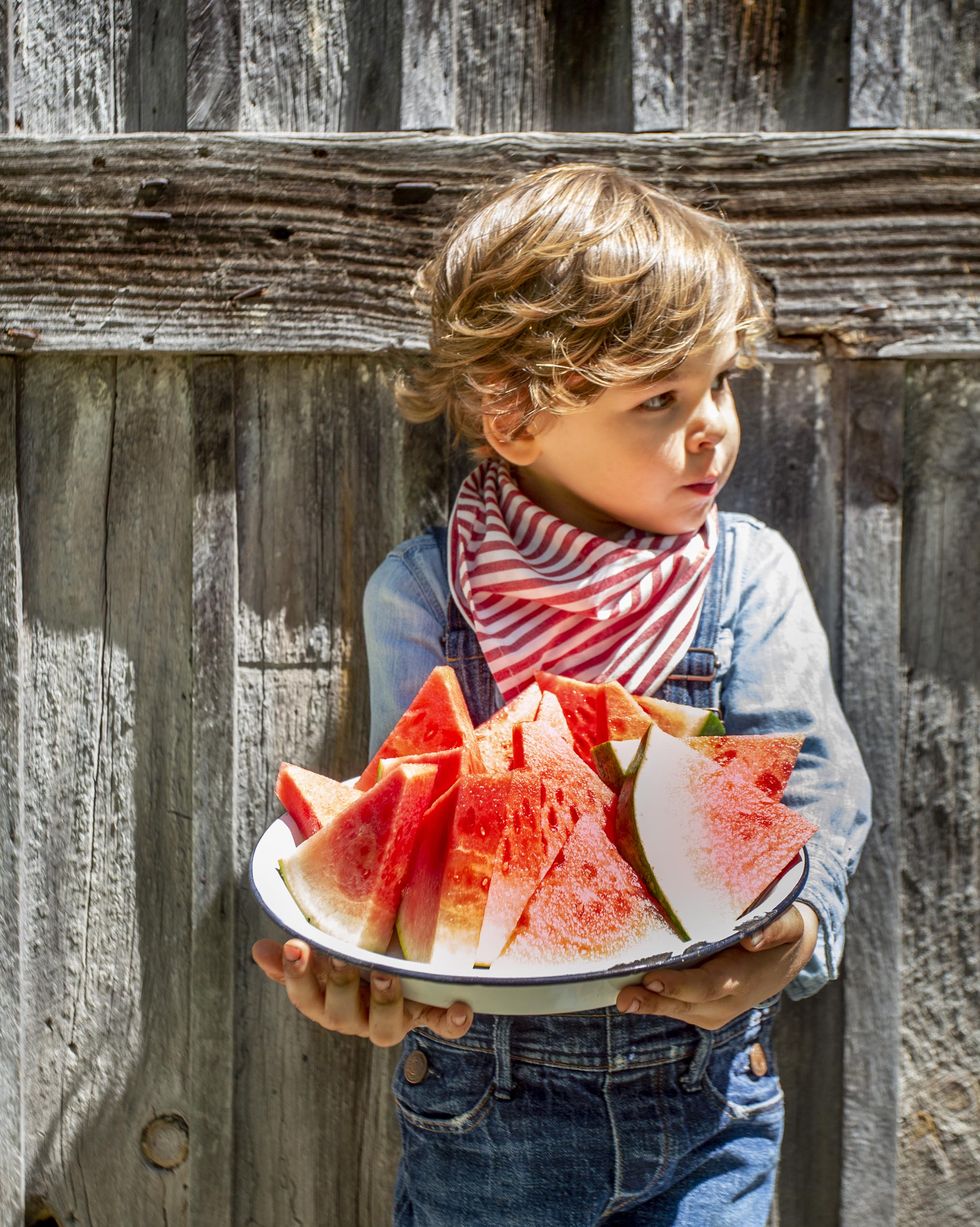small boy holding a tray full of cutup watermelon