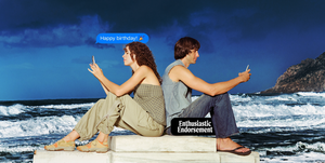 a man and woman sitting on a dock by the water phones in hand