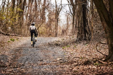 cyclist riding up a gravel road in cool weather