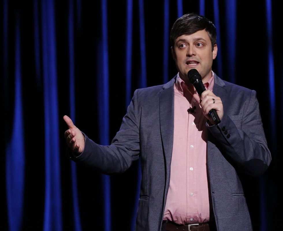 man holding a microphone and speaking in front of a large curtain