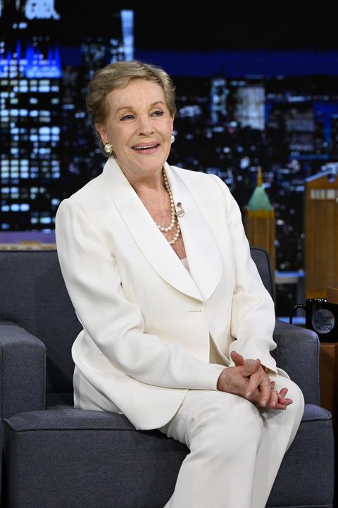julie andrews smiling as she sits on a chair