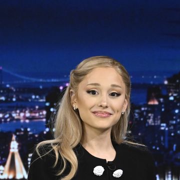 ariana grande with blonde hair and a black dress sat on a tv studio chair