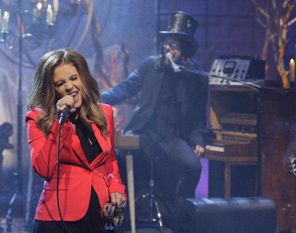 lisa marie presley performing in a red suit and singing into a microphone