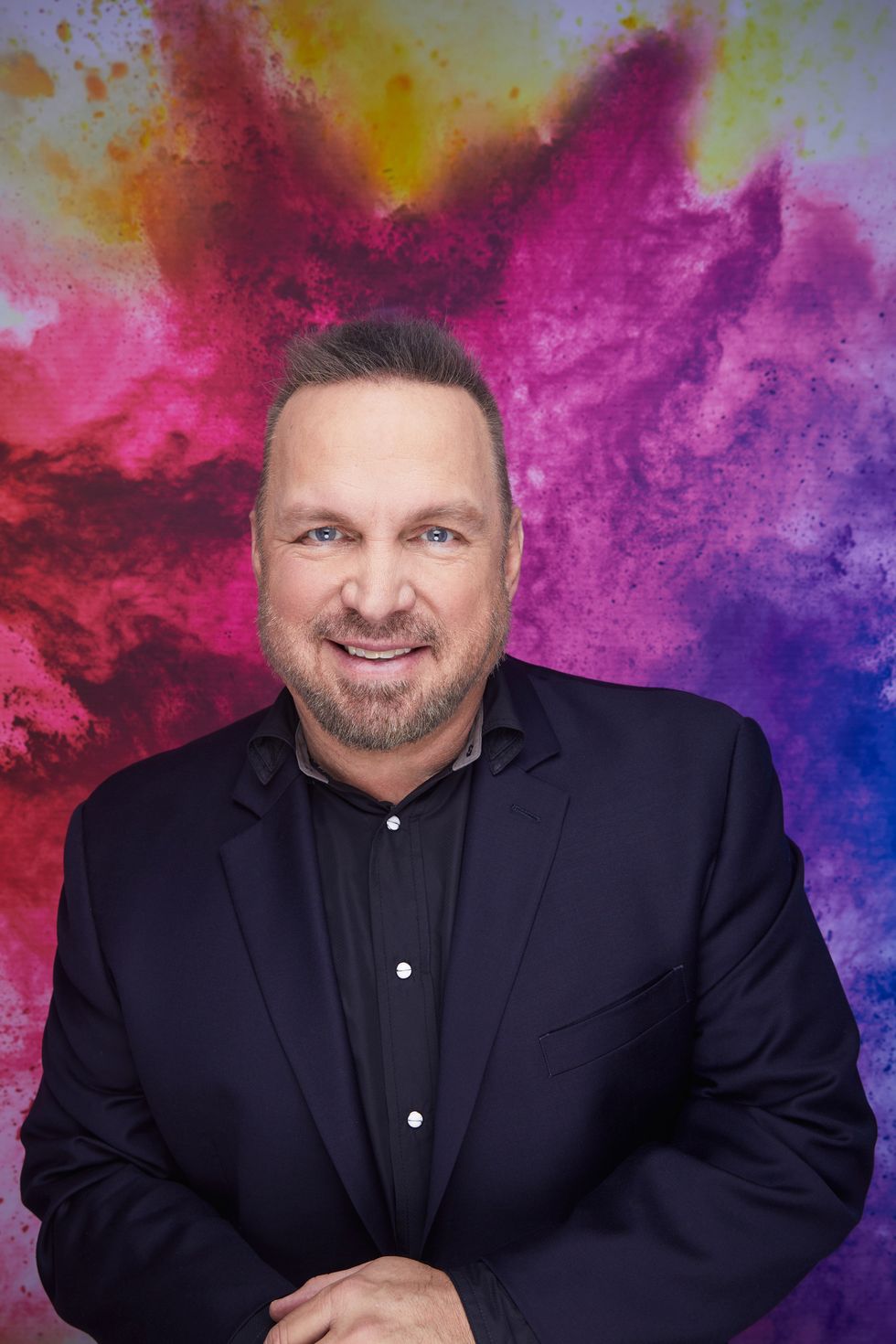 garth brooks posing with his hands on his knee and smiling for a promotional picture