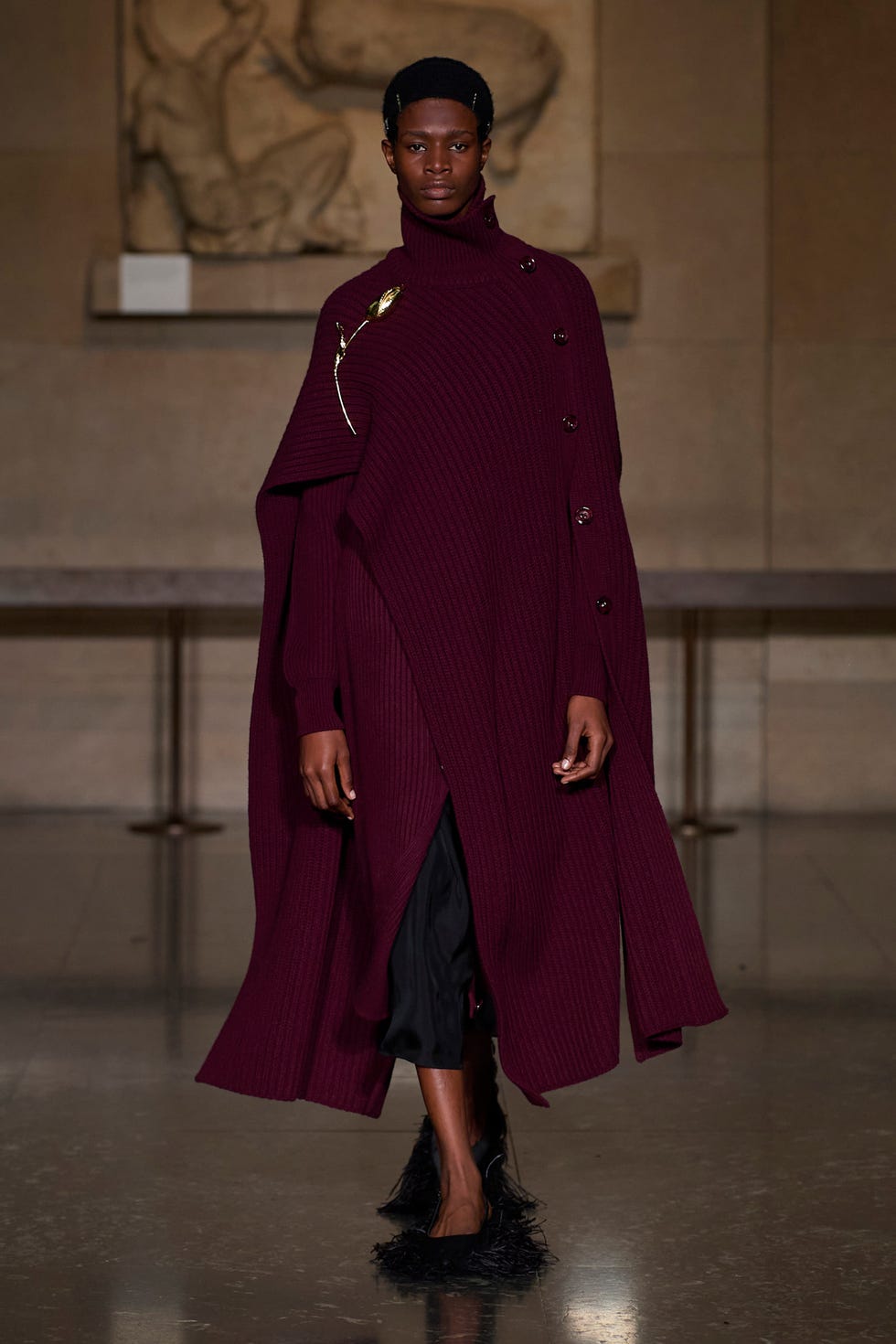 Fashion model showcasing a maroon knitted outer garment with an elegant design