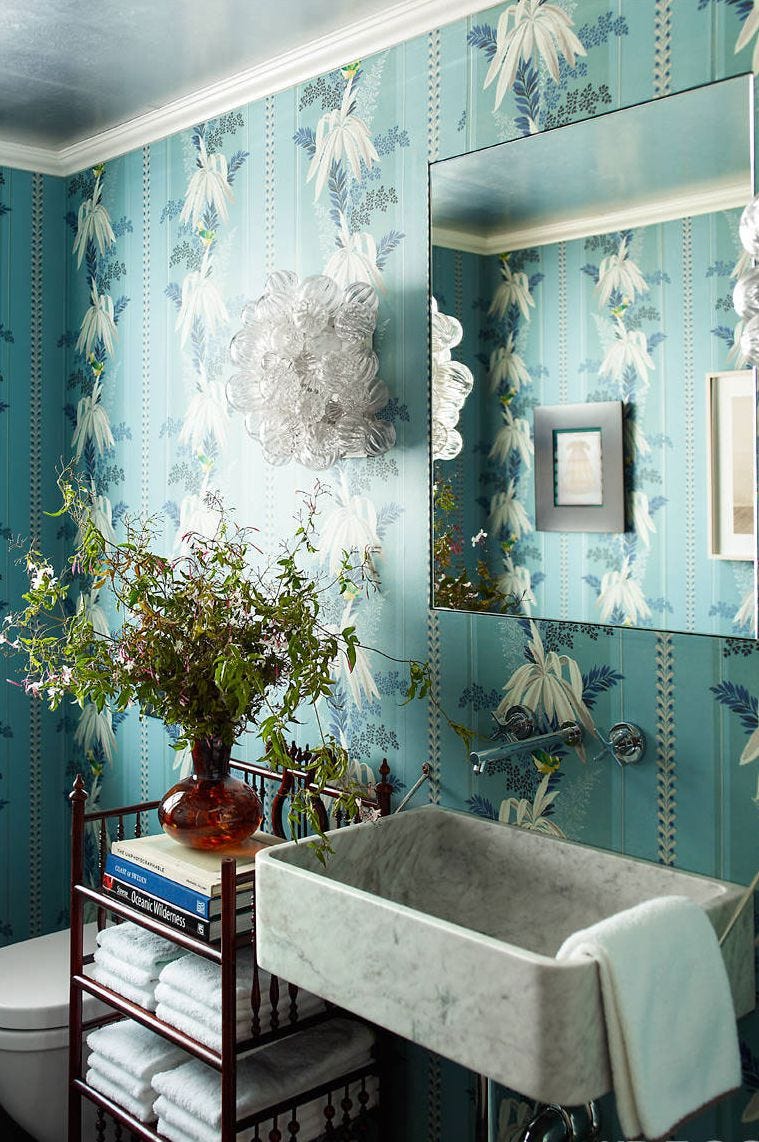 bathroom with blue floral wallpaper bathroom with blue floral wallpaper, black standalone shelf, marble sink, and bouquet