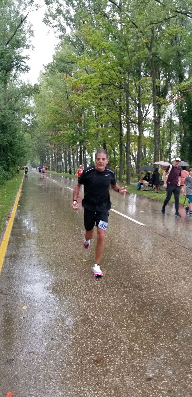 a man running on a road with trees on either side of it