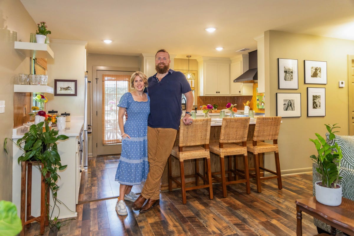 a couple standing together in a modern kitchen with wooden floors and a bar area