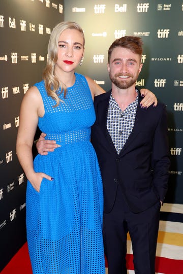 erin darke in a blue dress and with daniel radcliffe who is wearing a black suit and checkered tie