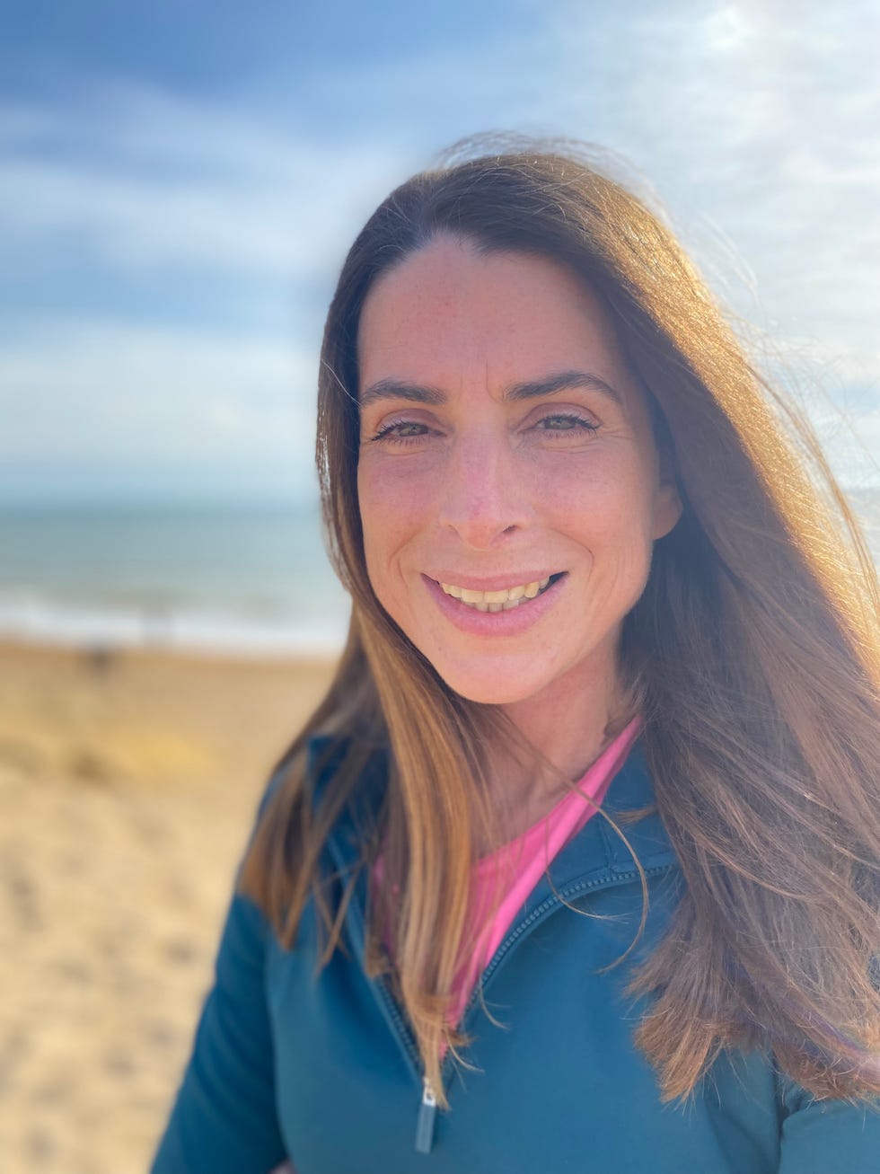 person standing on the beach with the sea and sky in the background