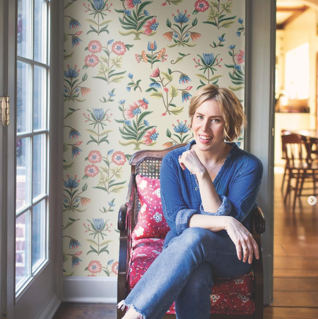 erin napier sitting in chair in front of wall with floral wallpaper
