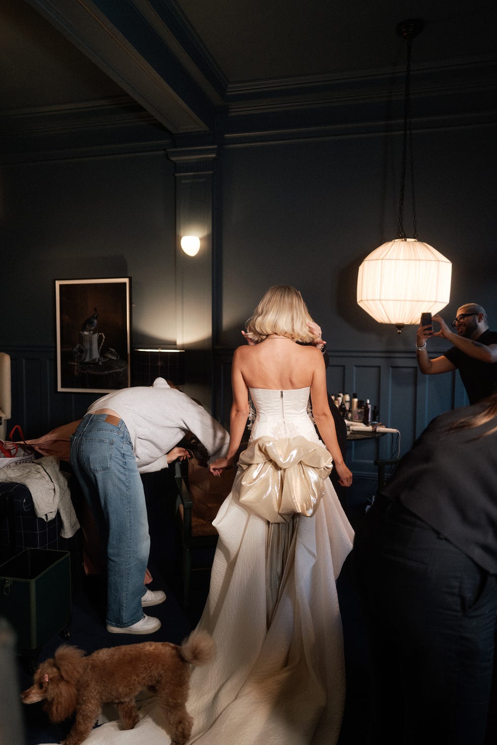 a blonde woman in a white dress is being assisted by a team in a stylish room