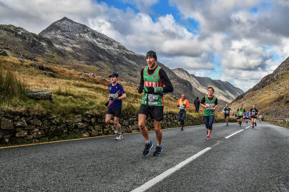 a group of people running on a road in the mountains